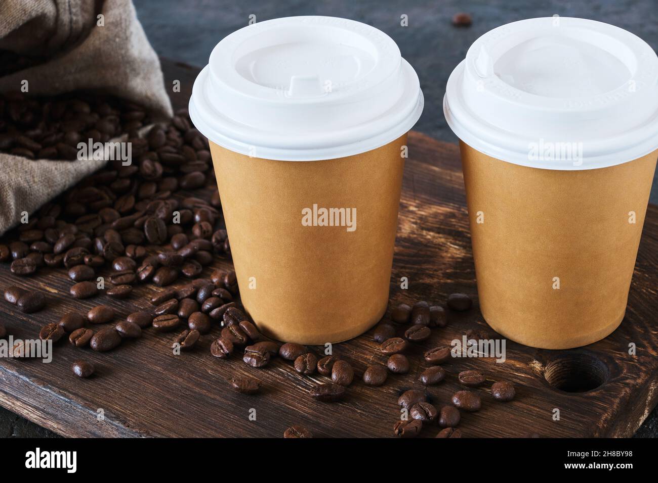 Two disposable coffee cups on table with scattered coffee beans Stock Photo