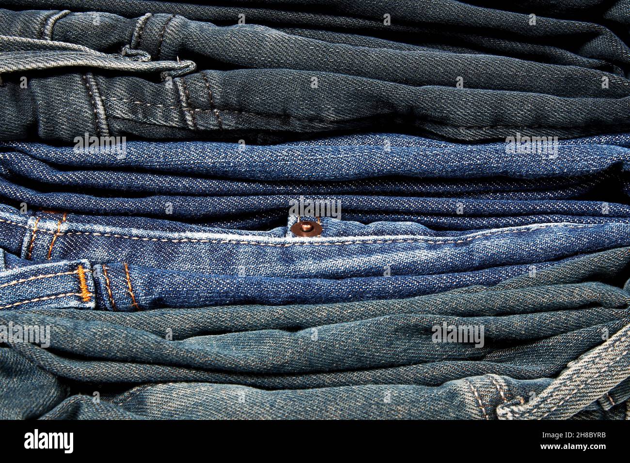 Stack of many blue jeans on the clothes shop shelf. Textile backgrounds and patterns Stock Photo