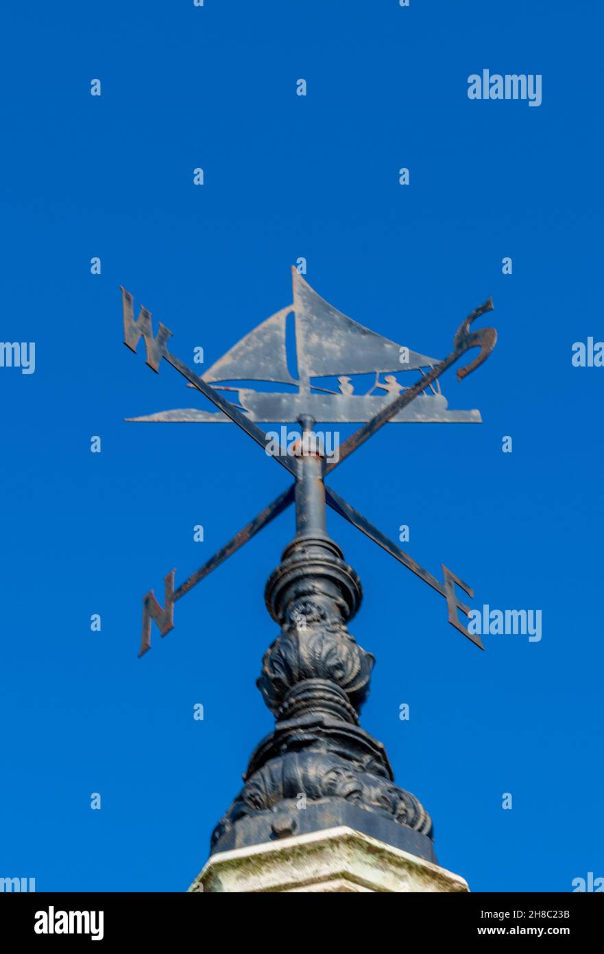 sailing boat or yacht design weather vane, wind direction indicator, sailing boat designed wind direction weather vane against a clear blue sky. Stock Photo