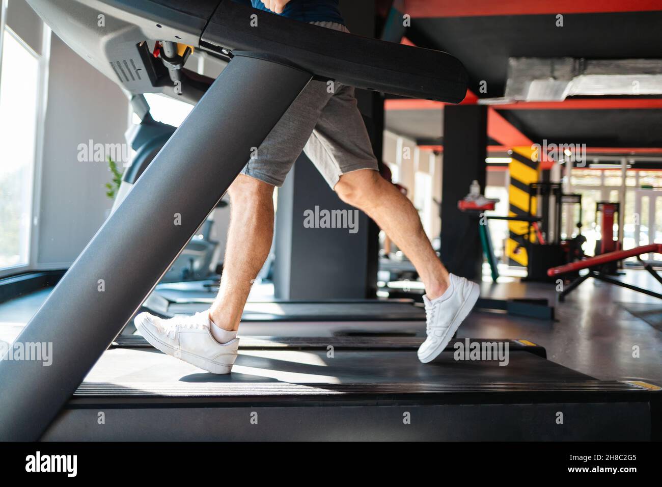 A sporty man runs on a treadmill in the gym. Legs closeup. The concept