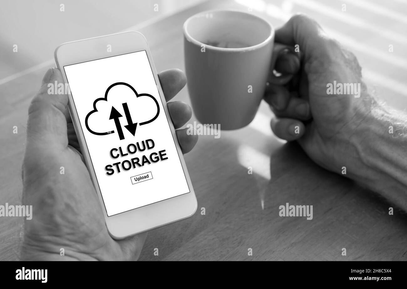 Male hands holding a smartphone with cloud storage concept and a cup of ...