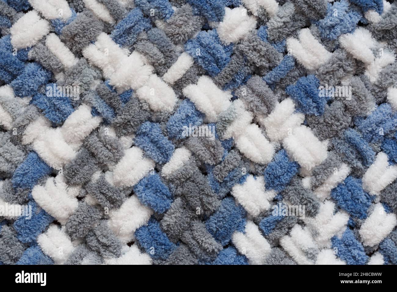 Fluffy knitting structure of gray, blue and white threads, close-up view from the top Stock Photo
