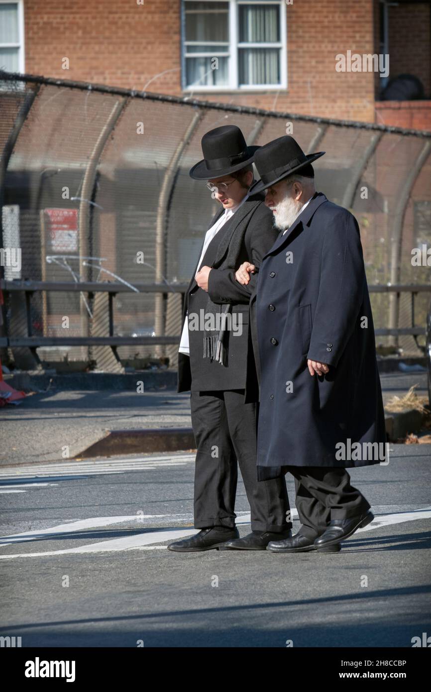 An orthodox jewish man crosses the street with help of a younger man, possibly his grandson. On an autumn day,. In Williamsburg, Brooklyn, New Yor. Stock Photo