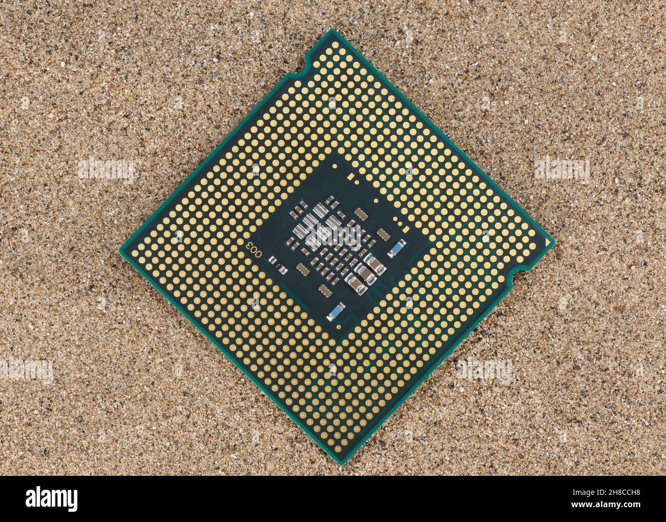 The microprocessor lies on the sand. Concept for the production of silicon semiconductors from sand. Stock Photo