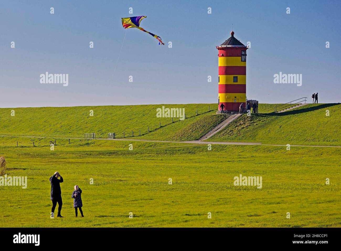 persons flying a kite at lighthouse of Pilsum, Germany, Lower Saxony, East Frisia, Pilsum Stock Photo