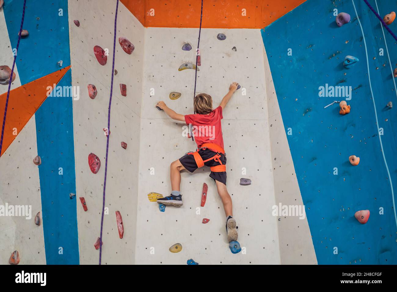 Boy at the climbing wall without a helmet, danger at the climbing wall Stock Photo