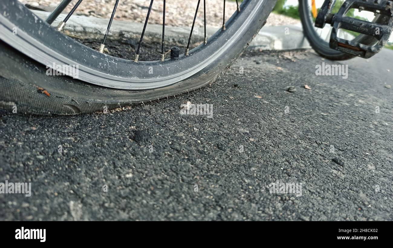 The flat tire of a bicycle closeup photo. Road accident punctured tire, deflated bicycle wheel