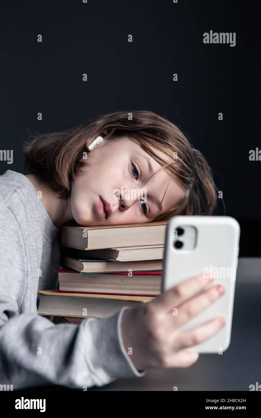 Little girl with books and a phone in her hands Stock Photo - Alamy