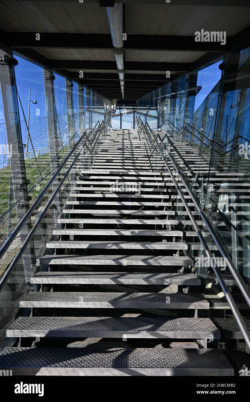 A modern light-flooded steel staircase protected from environmental influences by glass. Stock Photo