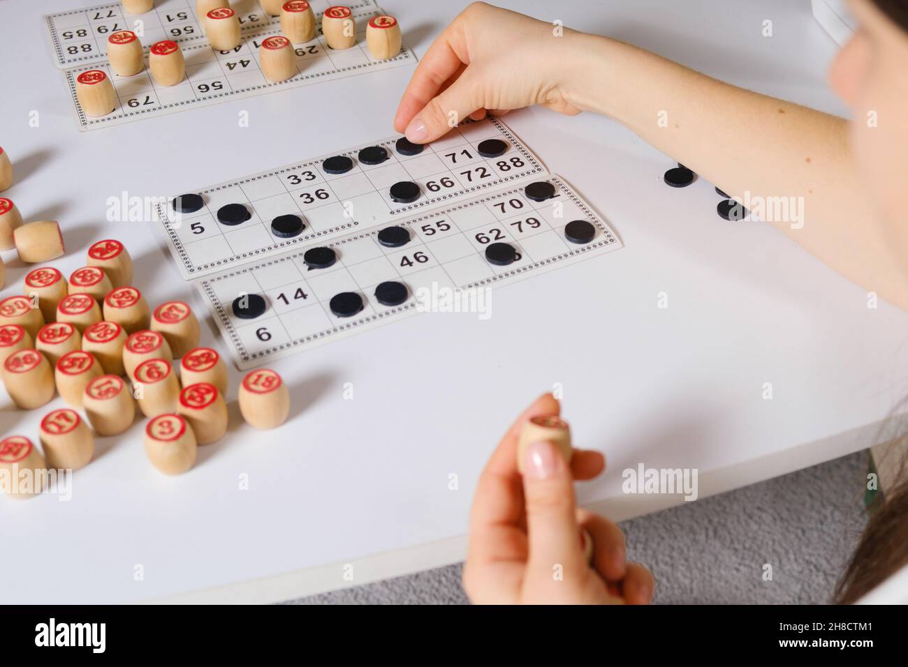 A woman plays a table game of Russian lotto, closes cards with numbers with chips. Stock Photo