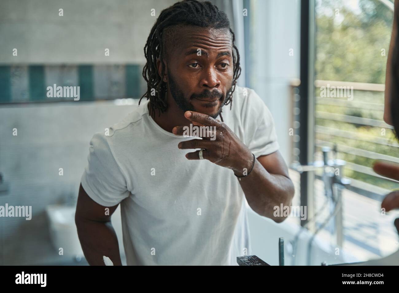 Focused guy examining skin on his face Stock Photo