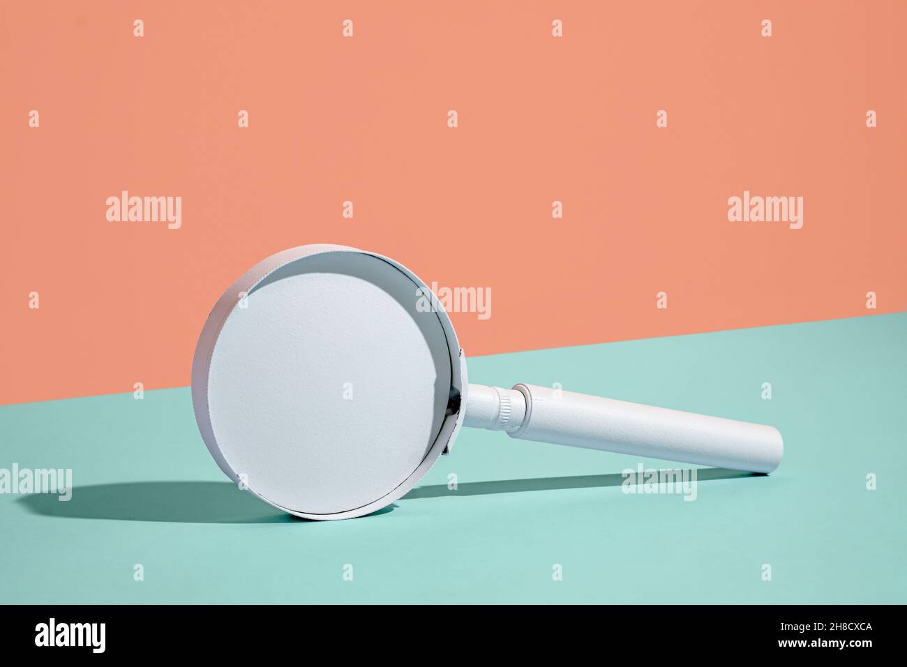 Plain white small handheld magnifying glass balanced on edge over a