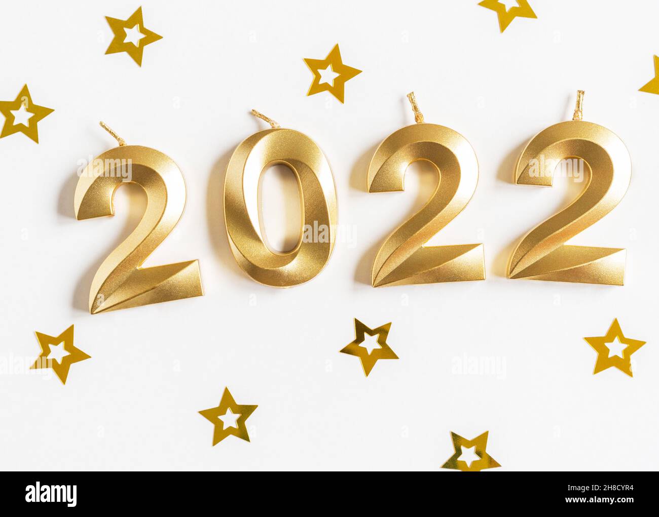 Greeting card - happy new year with numbers 2022, gold stars glitter on white background. Minimal holiday concept. Top view. Flat lay Stock Photo
