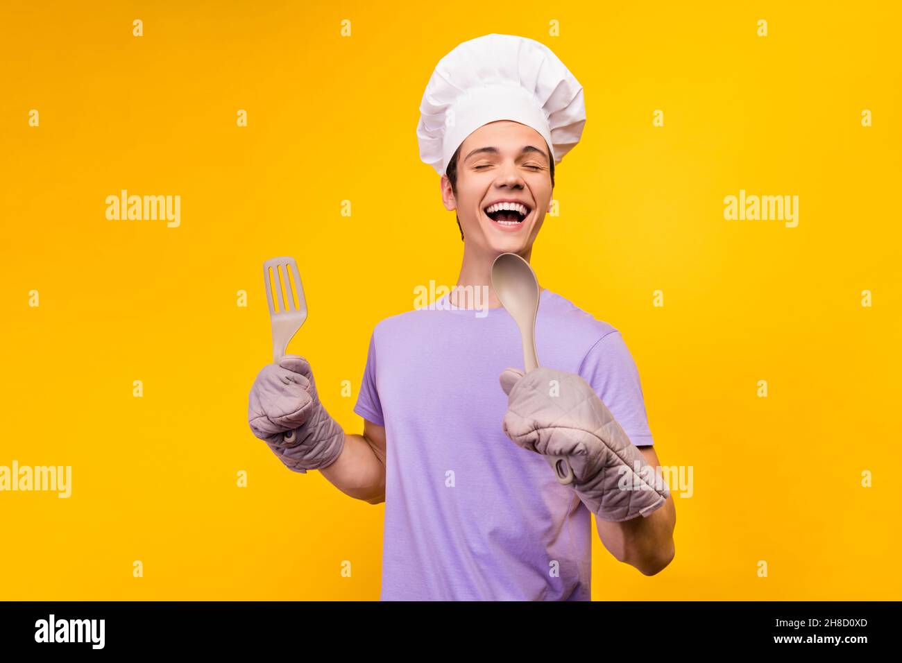 Portrait of attractive cheerful guy cooking meal gourmet recipe singing ...