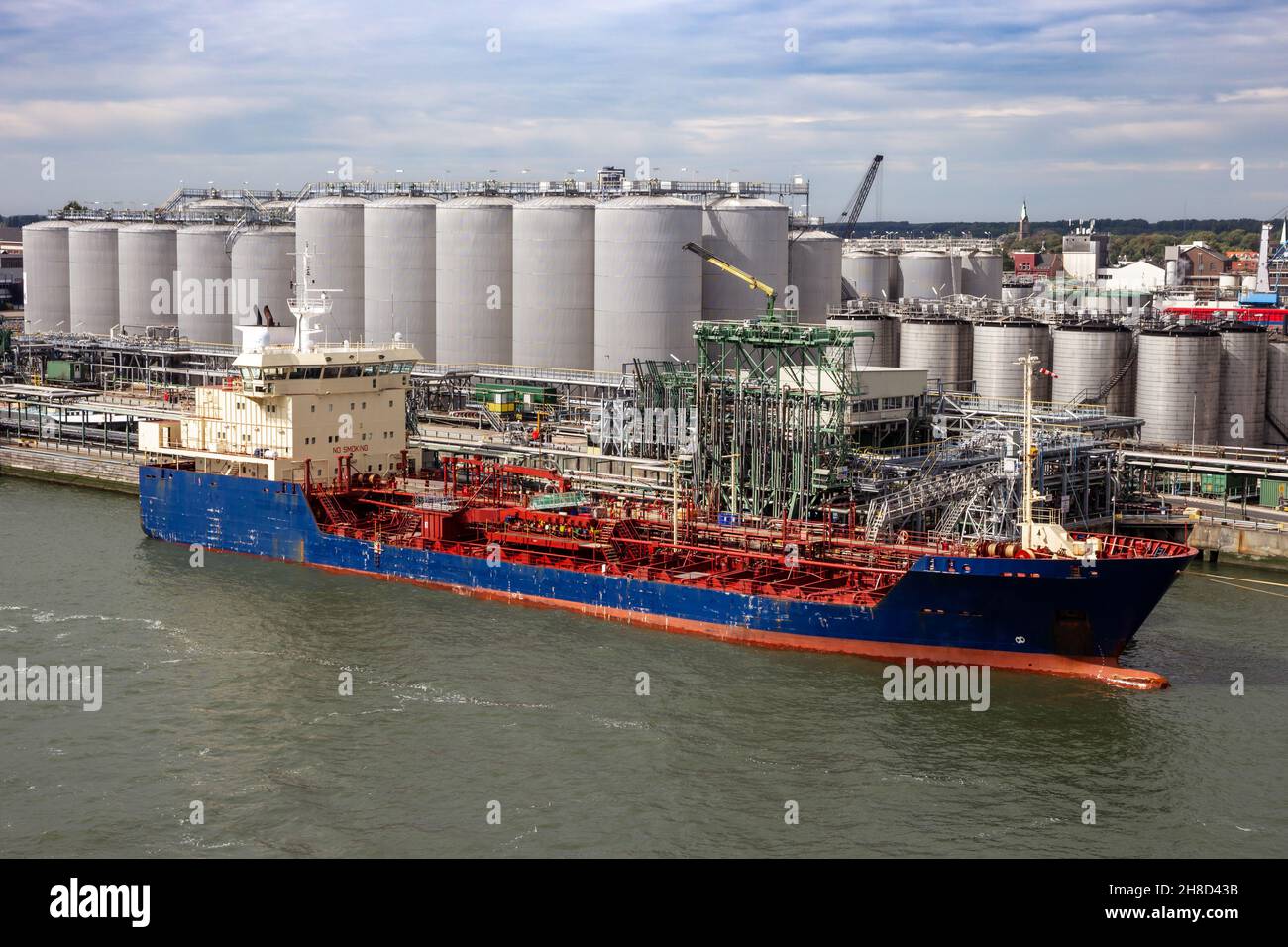 Oil tanker moored an oil terminal with fuel storage silos in an industrial port Stock Photo