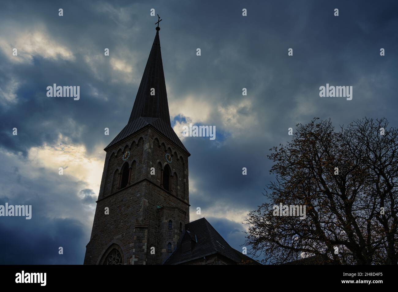 church spire in Essen Heisingen in front of a cloudy sky at dusk. Stock Photo