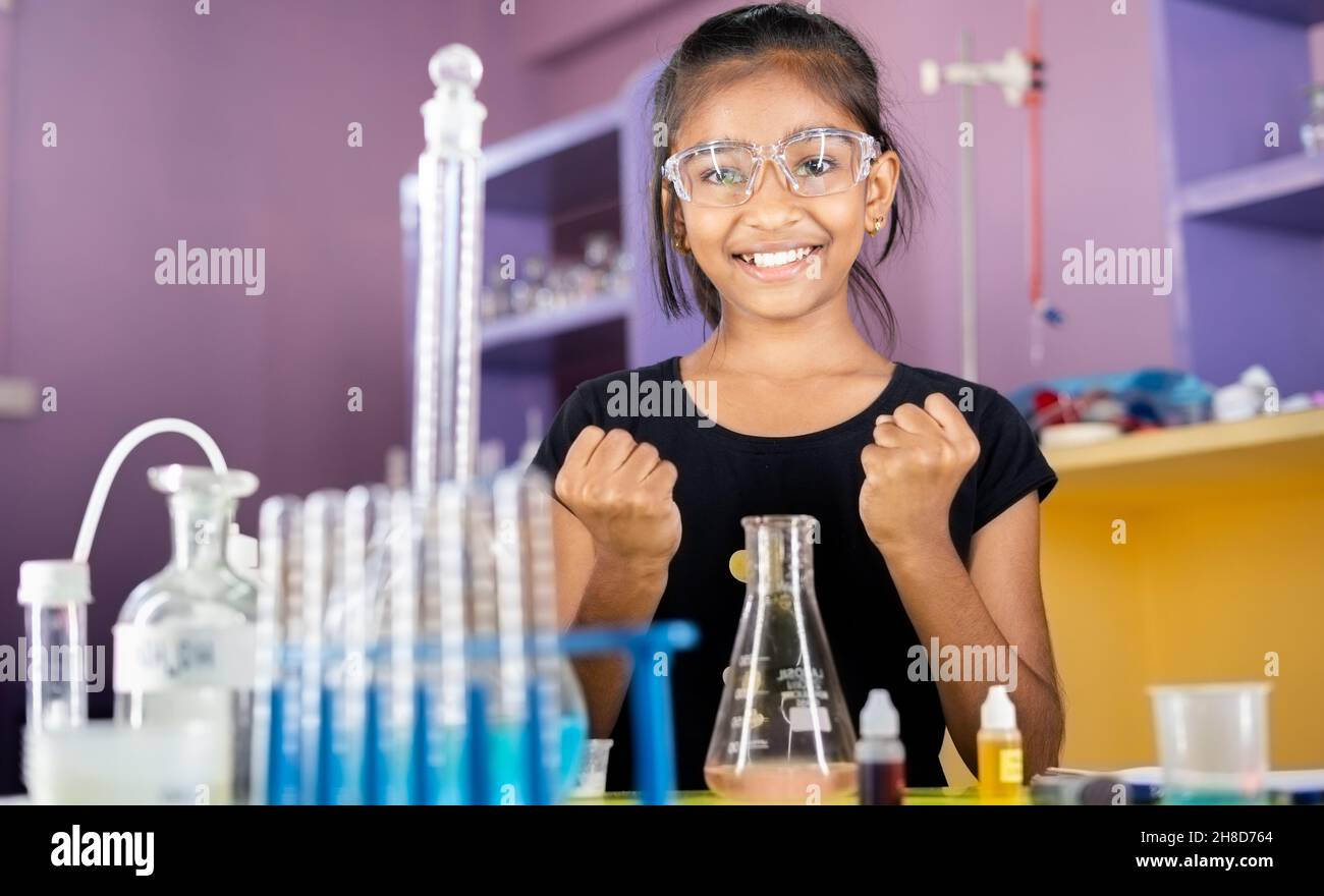 Excited Kid celebrating over successful science experiment result or chemical reaction at chemistry laboratory - concept of child prodigy, intelligent Stock Photo