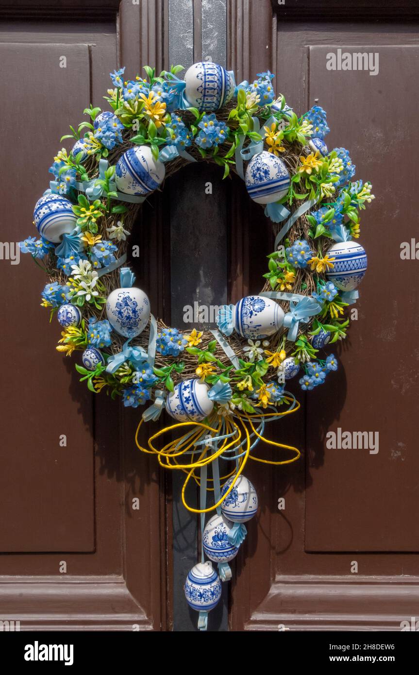 An ornate floral wreath, with blue and white porcelain baubles, hanging on a brown wooden door in Prague Castle's medieval Golden lane Stock Photo