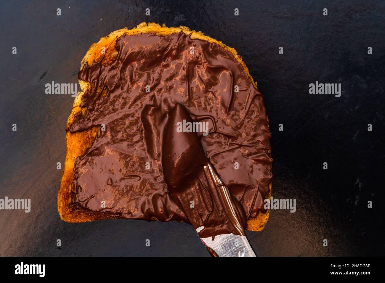 Spreading chocolate cream on toasted bread Stock Photo