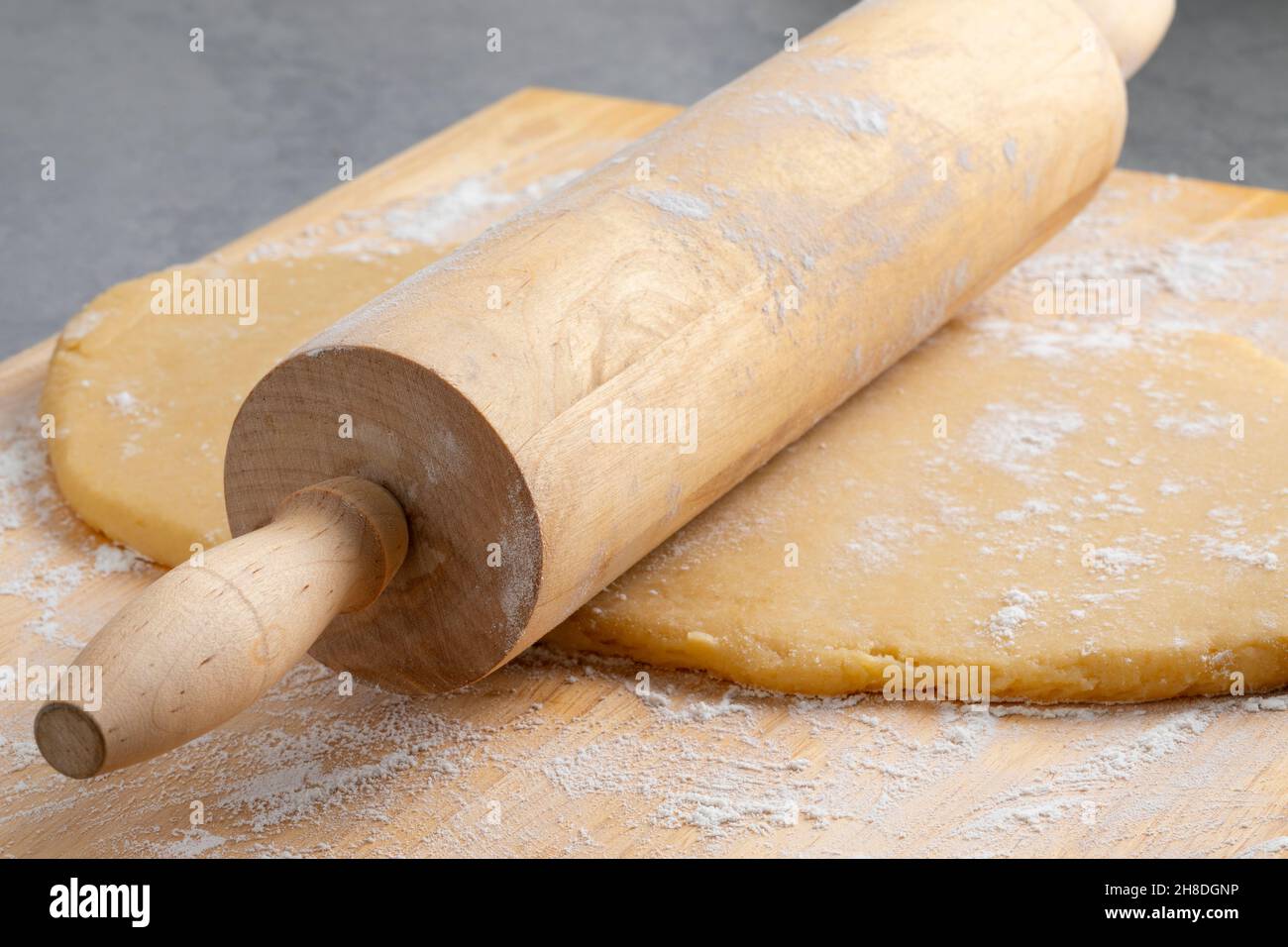 Preparing fresh dough for baking with a wooden rolling pin and flour