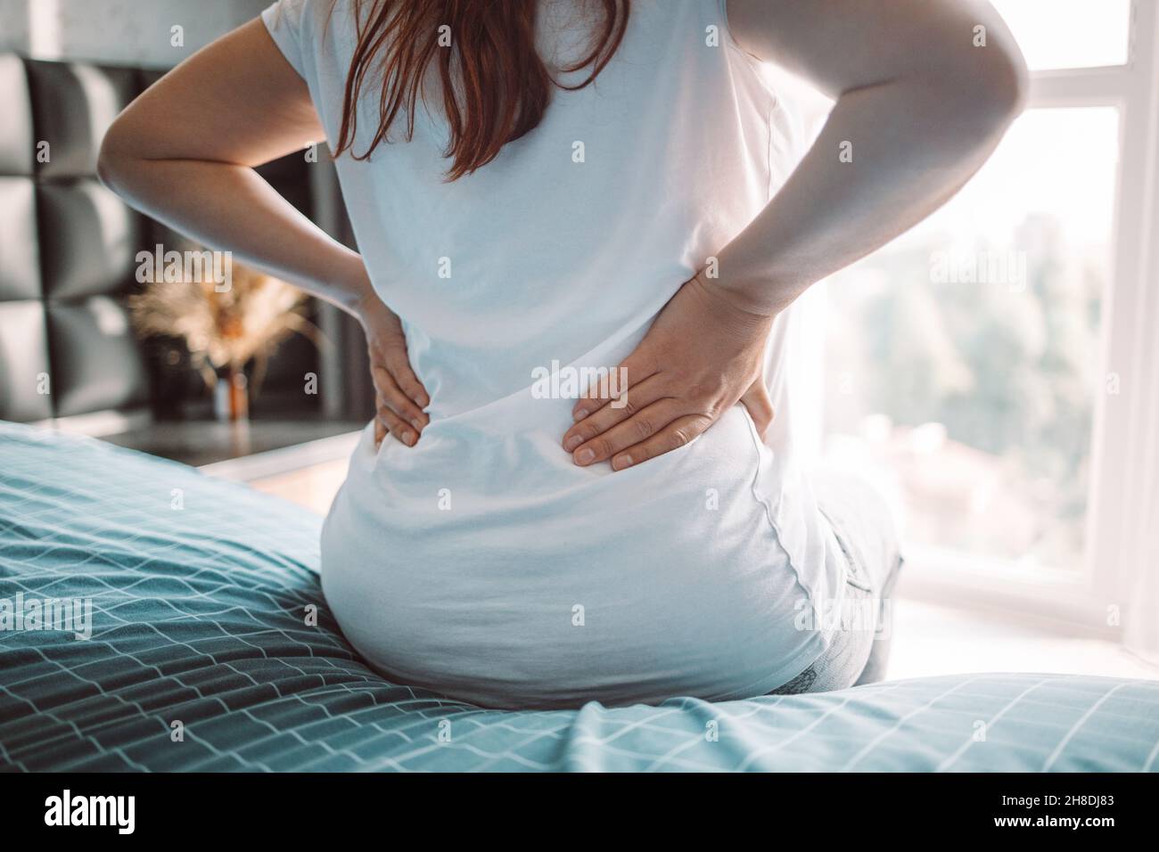 Back view of young woman waking up in bed with backache Stock Photo Alamy