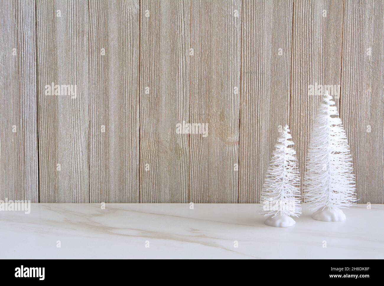 Little white trees on stone table with weathered wood background.  Seasonal decor with room for text in horizontal orientation. Stock Photo