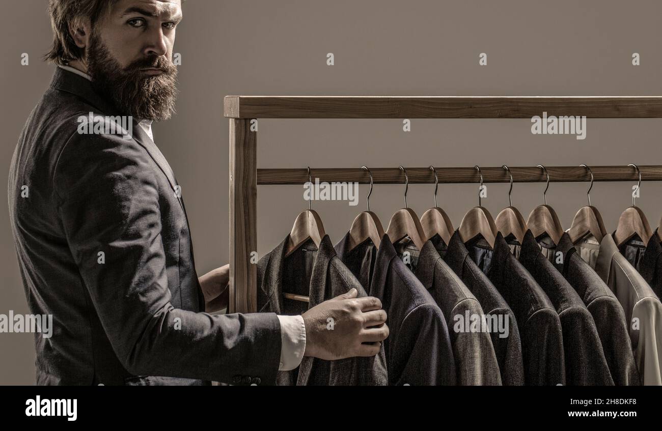 Tailor, tailoring. Men's suit, tailor in his workshop. Elegant man's suits hanging in a row. Luxury mens classic suits on rack in elegant men's Stock Photo