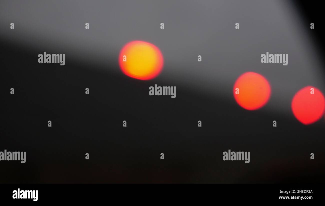 Three defocused red orange lights against grey background with copy space Stock Photo