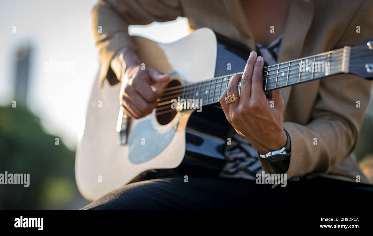 Close up of Latin man playing guitar on the street during sunset Stock Photo