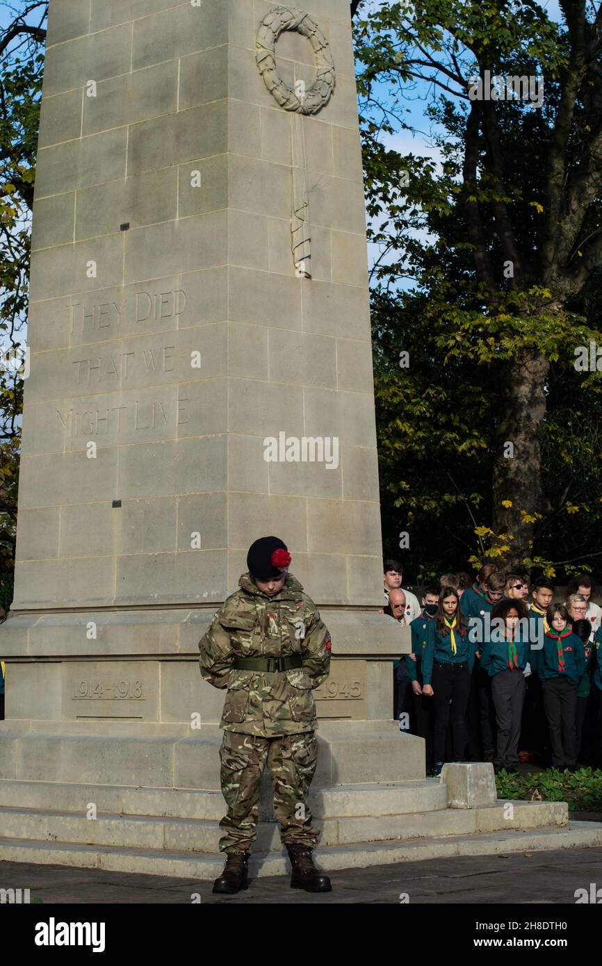 Remembrance Sunday parade with cadet in front of Stretford War Memorial, head bowed. Chester Road, Stretford. Text They Died That We May Live Stock Photo