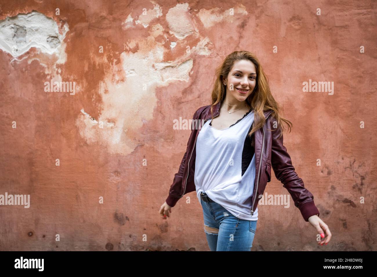 Young and happy girl in casual clothes on a red wall background with copy space Stock Photo