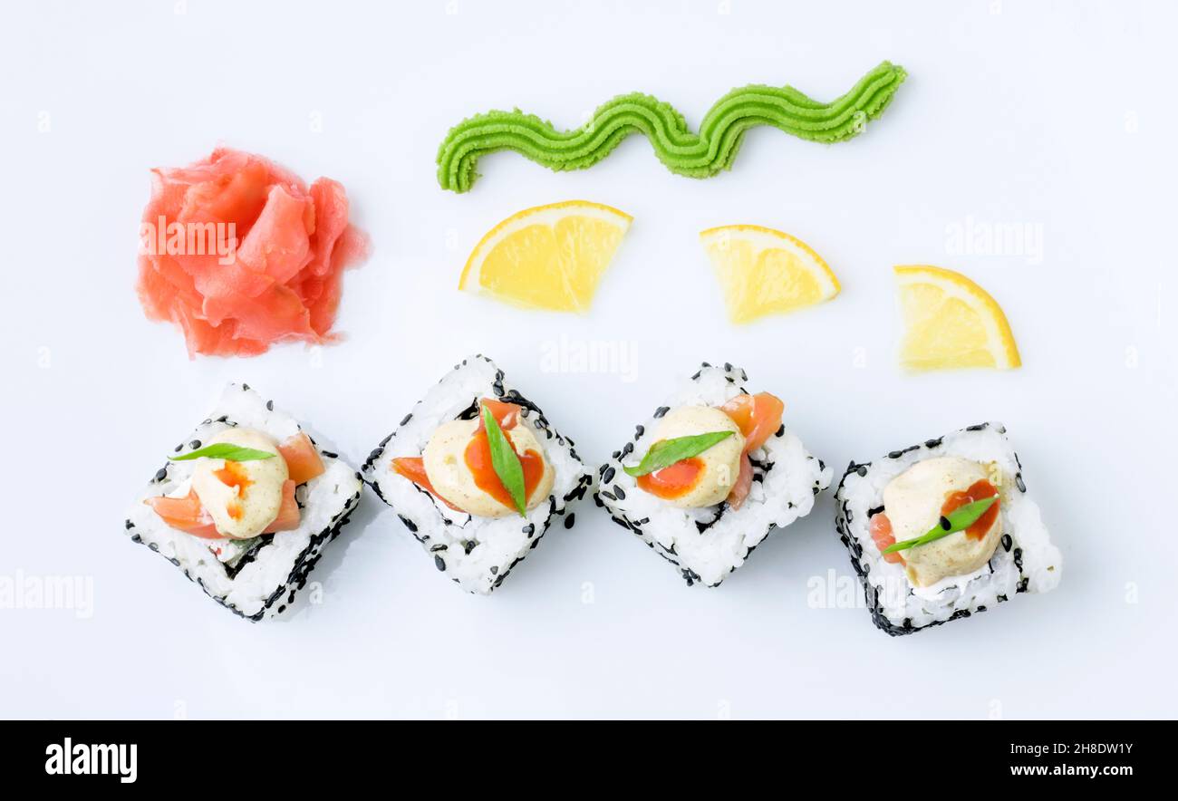 Sushi rolls are served on a white background with lemon, ginger and wasabi. Concentia of Japanese cuisine, spring food, baby food. Copy space Stock Photo