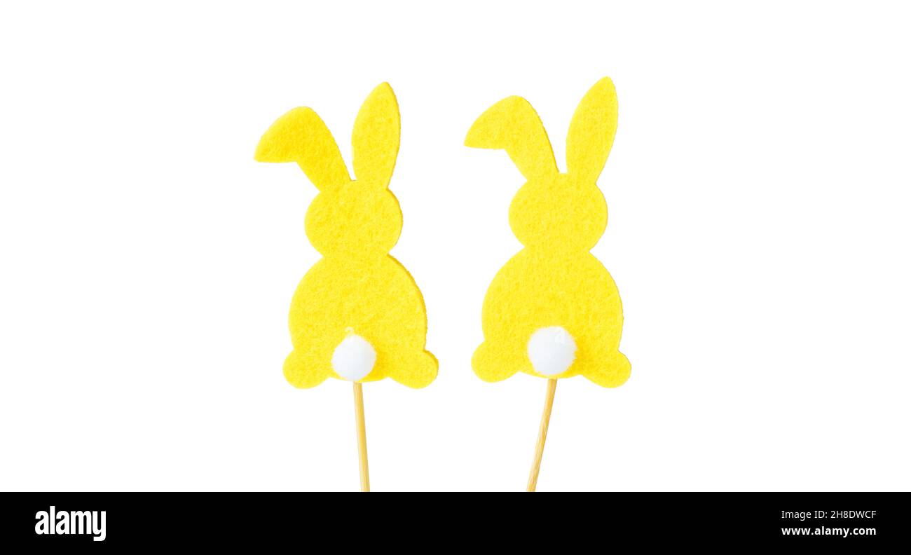 Yellow easter bunny rabbits with white tails, silhouette, on a wooden stick, isolated on a white background. Souvenir, decoration for Easter. Easter c Stock Photo