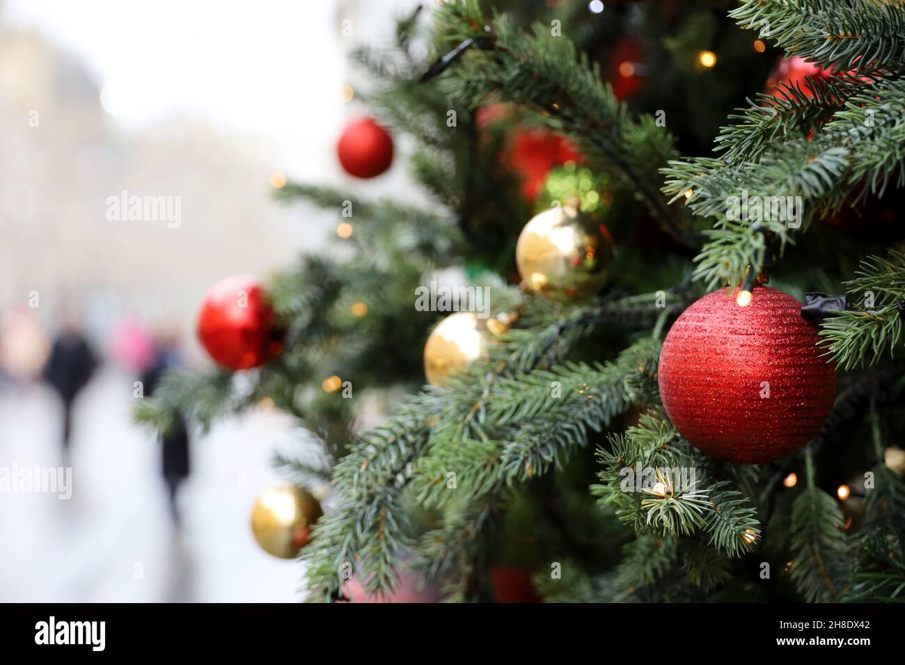 New Year decorations on a city street. Christmas tree with red and golden toy balls on blurred people background Stock Photo