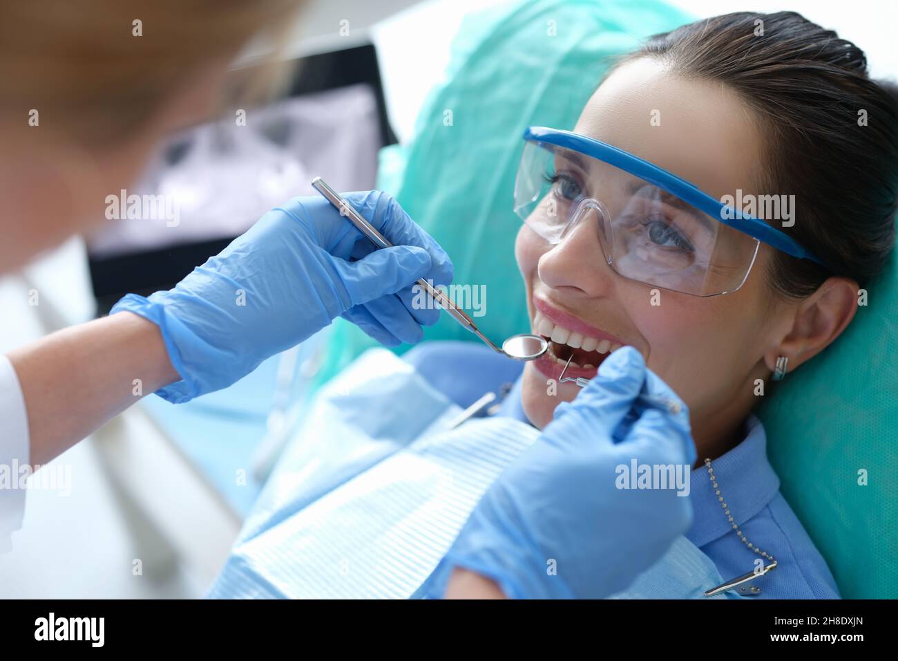 Doctor examining oral cavity of female patient using dental instruments in clinic Stock Photo