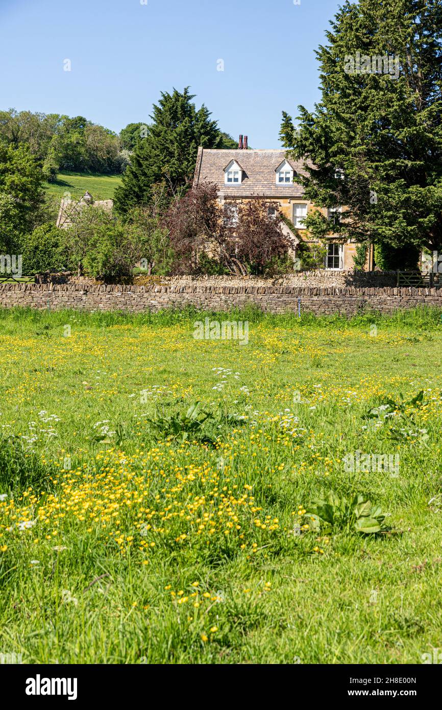 The Manor House beside the infant River Windrush as it flows through the Cotswold village of Naunton, Gloucestershire UK Stock Photo