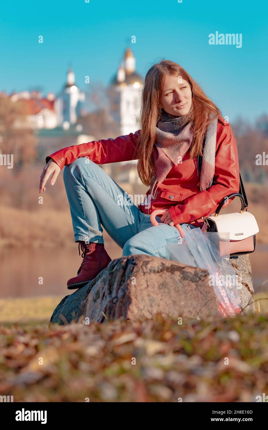 Girl resting sitting on a stone on a sunny day in late autumn Stock Photo