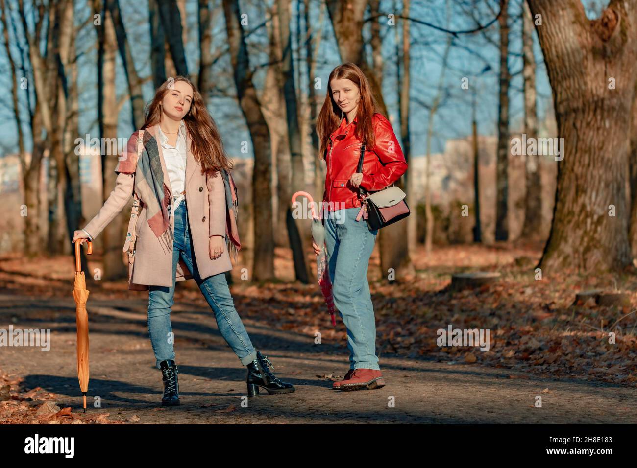 Two girls posing for a photo on a walk in the park on a sunny day in late autumn Stock Photo