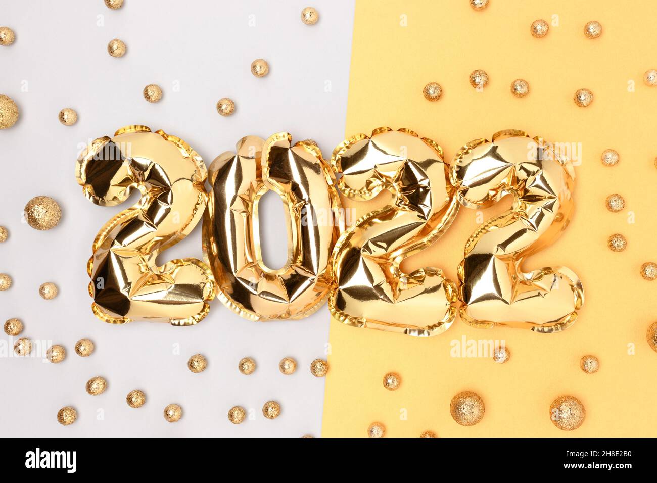 2022 inflatable golden balloons and golden round confetti. New Year's concept. Stock Photo