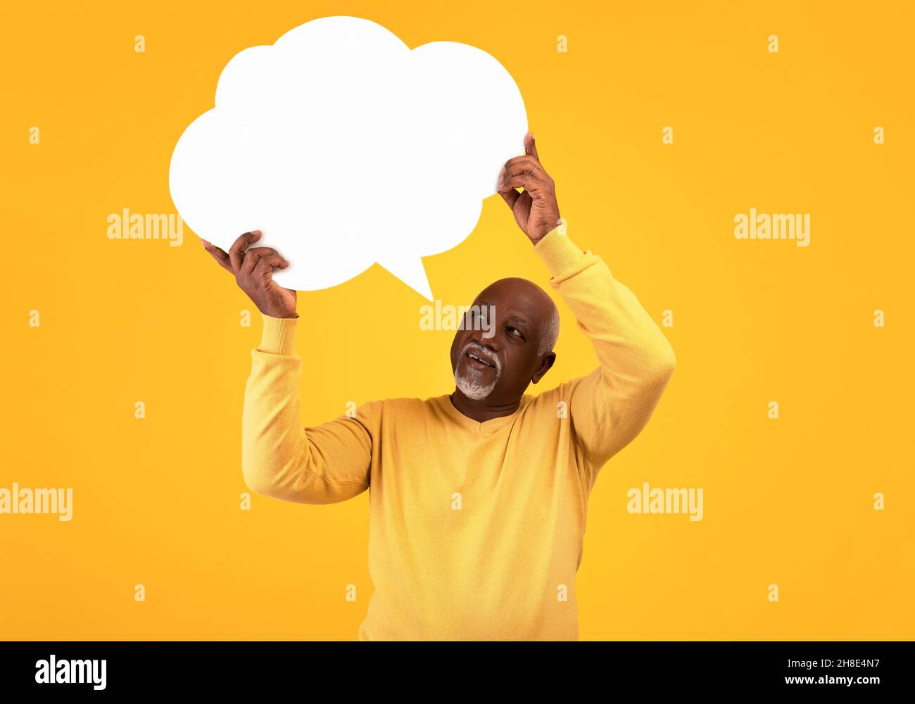 Elderly black man holding blank speech bubble with mockup for your ad on orange studio background Stock Photo