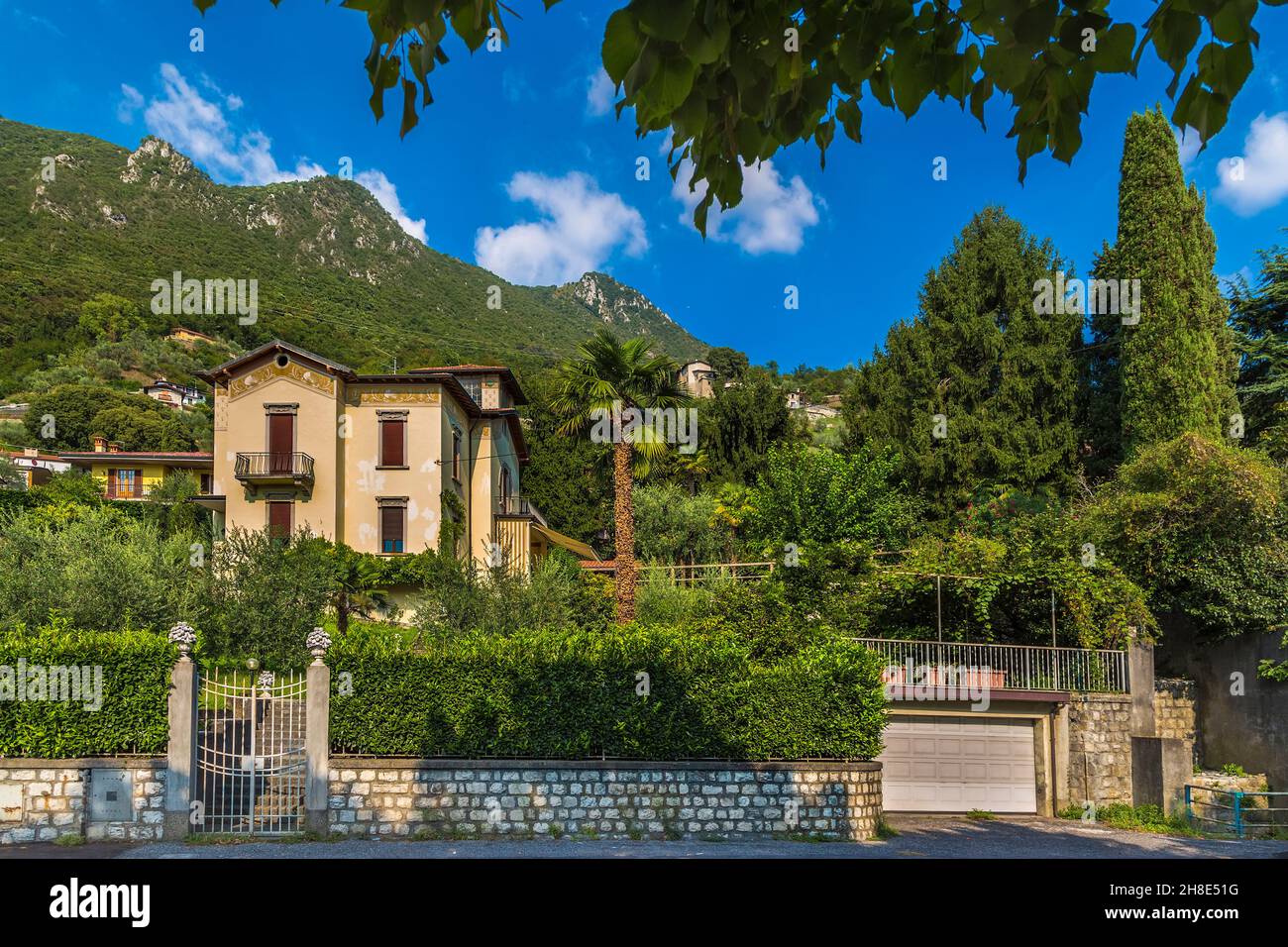 A small populated area with private houses and gardens on the backdrop of a mountain range. Sale-Marazino. Italy Stock Photo