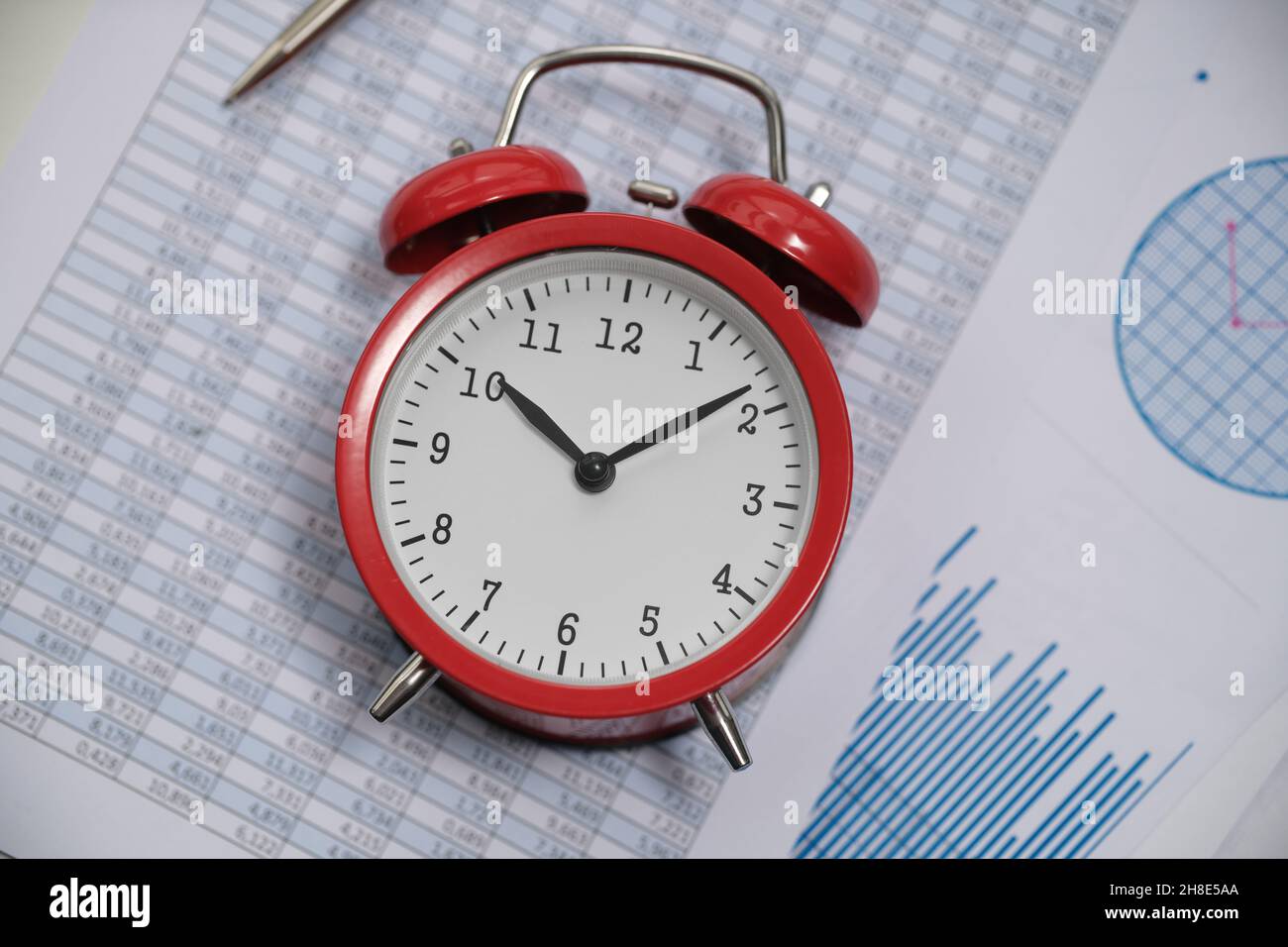Red alarm clock lying on documents with graphs and numbers closeup Stock Photo