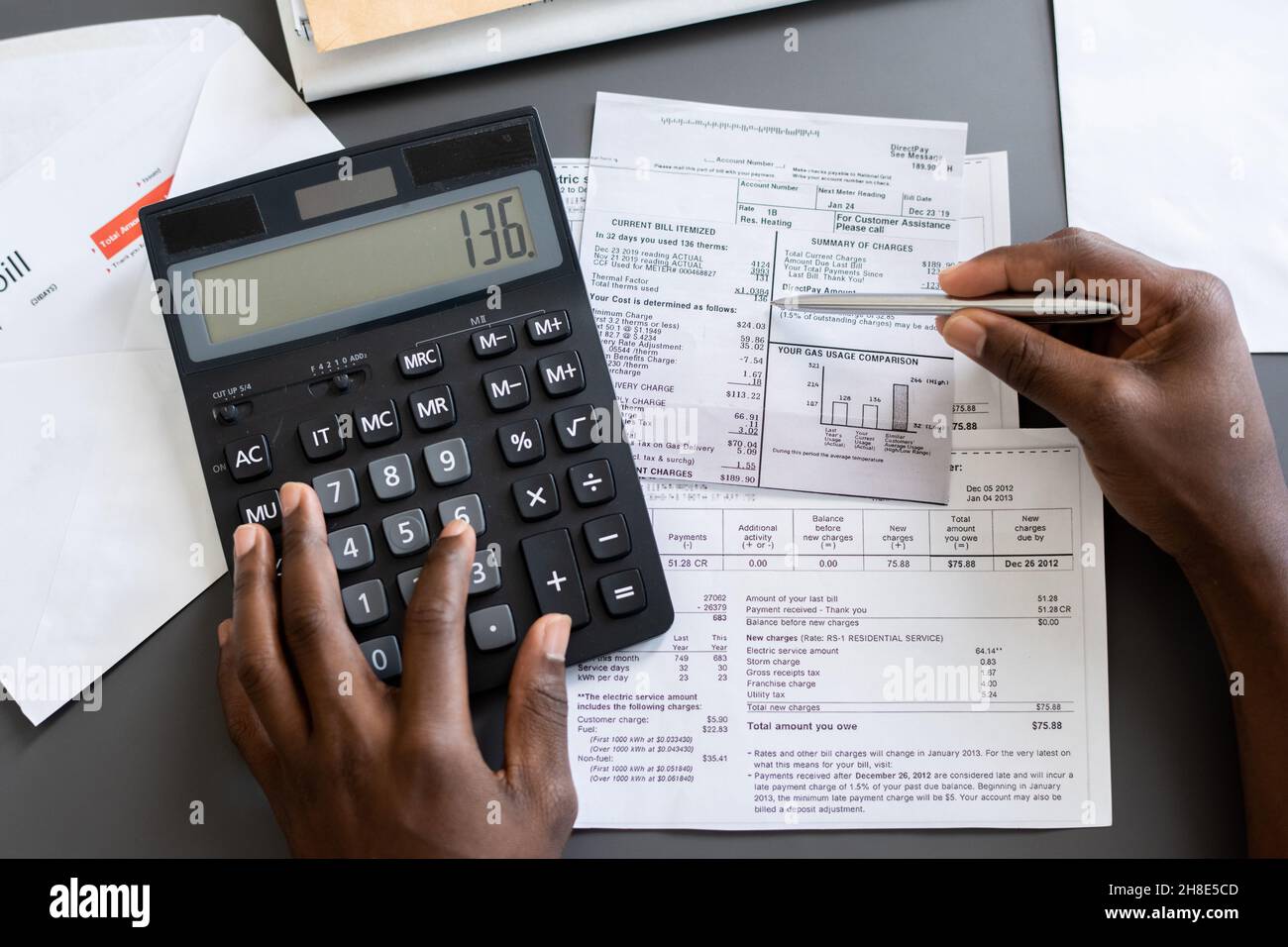 Above view of unrecognizable blackman checking receipts using calculator at table Stock Photo