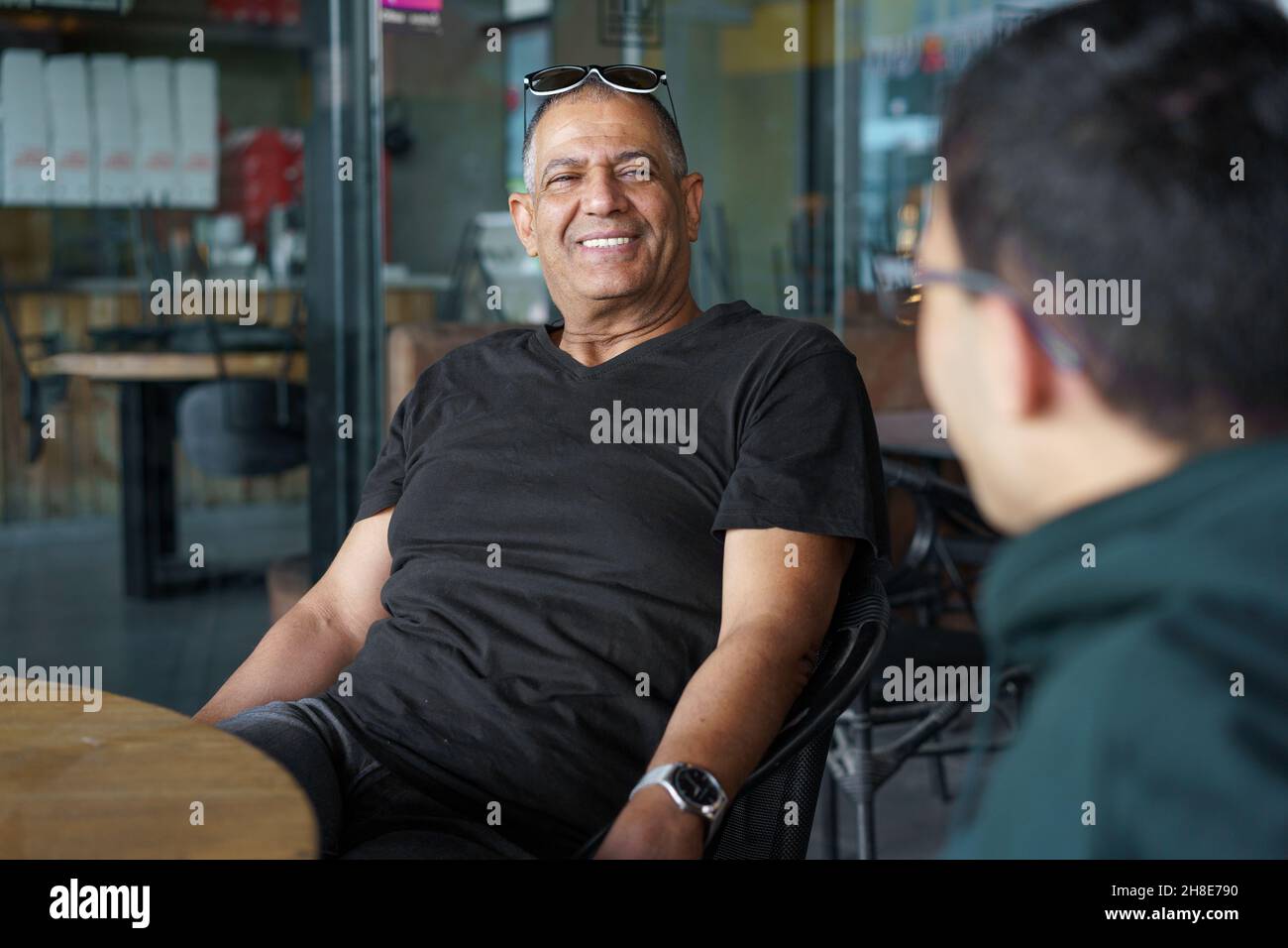 Senior man in coffee shop. Elderly man sitting with young son and