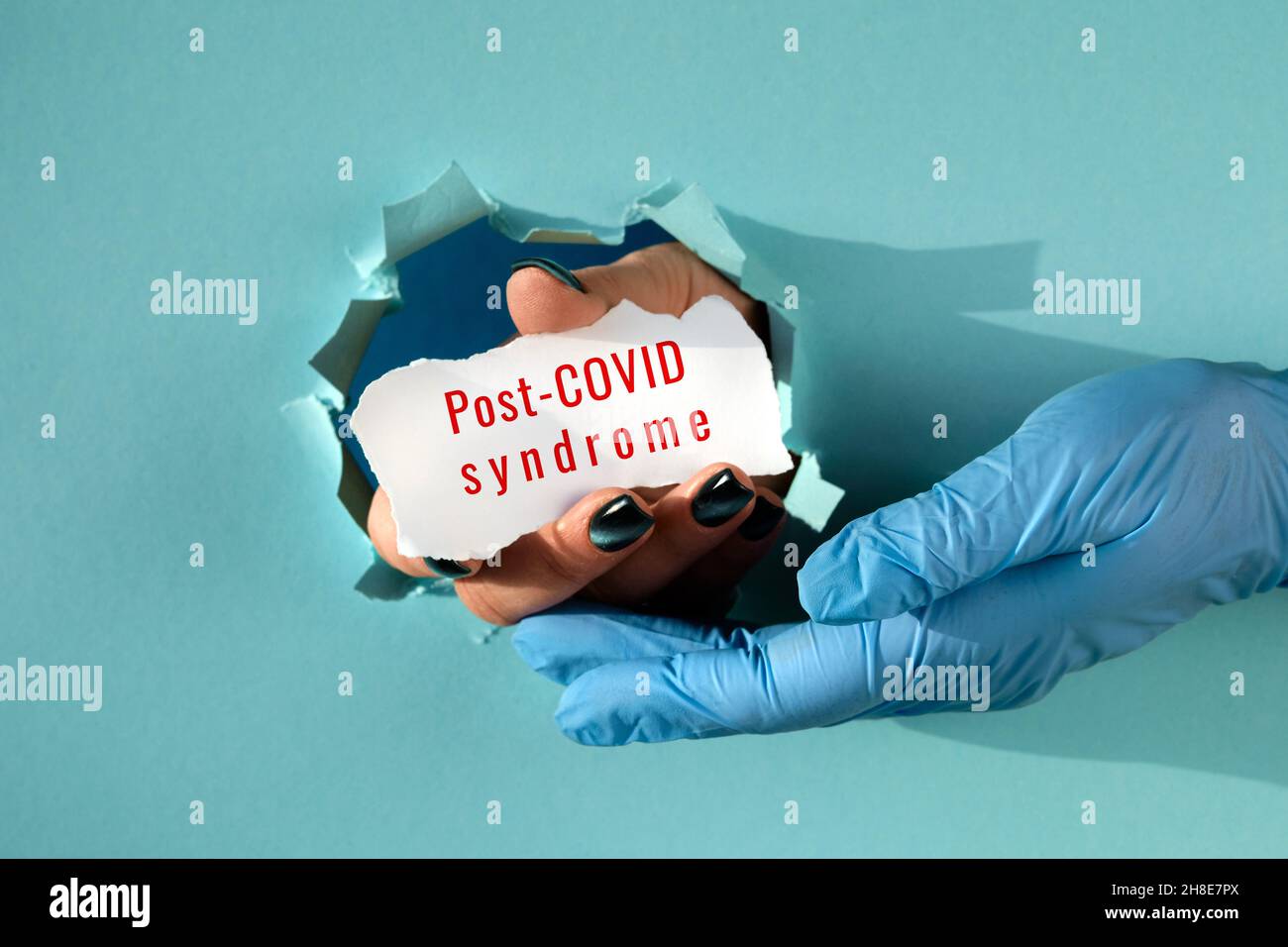 Post Covid syndrome, long covid. Hand in glove supporting hand with text on  scrap of paper in paper hole Stock Photo - Alamy
