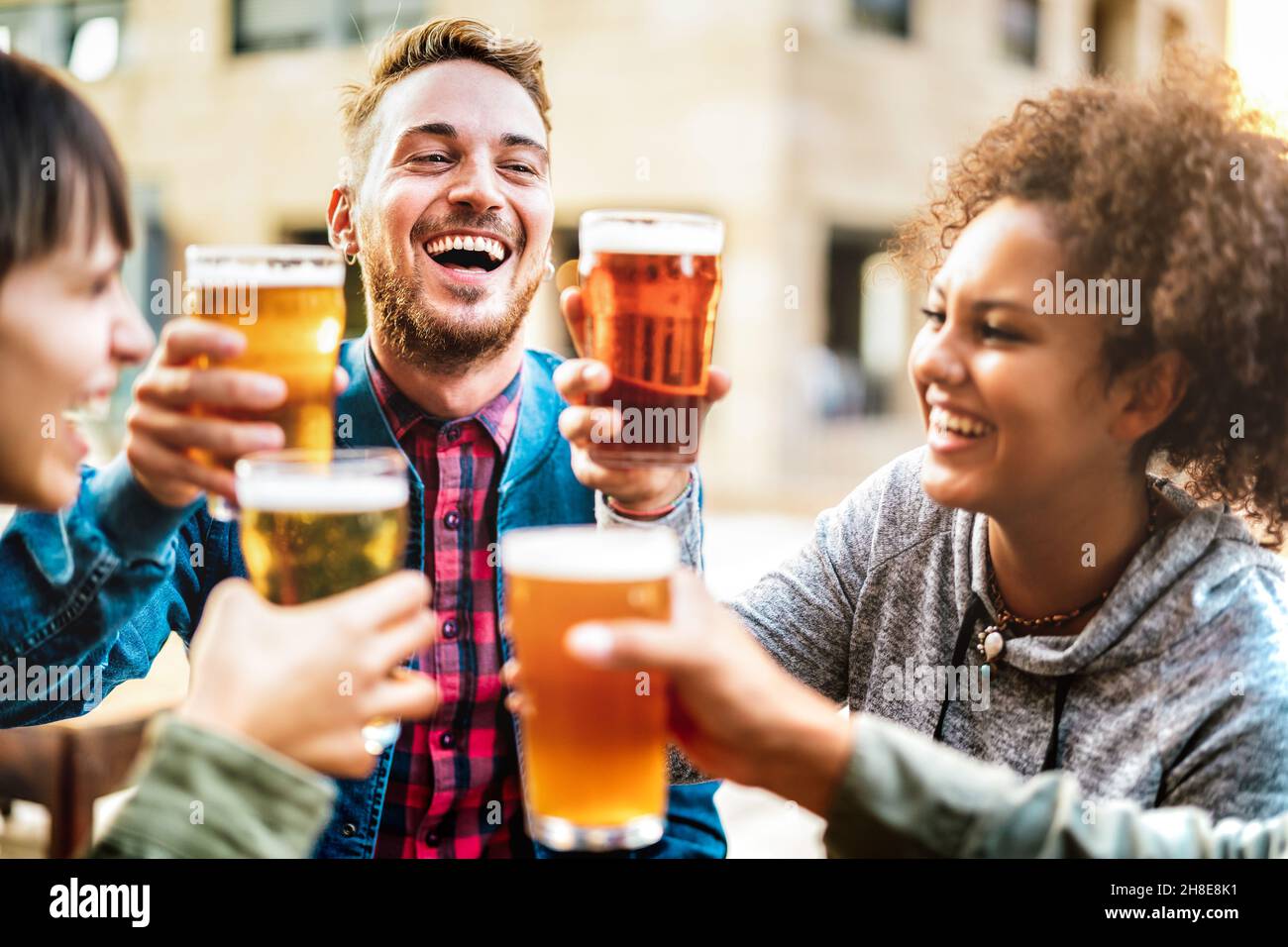 Multicultural happy friends drinking and toasting beer at brewery bar restaurant - Beverage life style concept with men and women having fun together Stock Photo