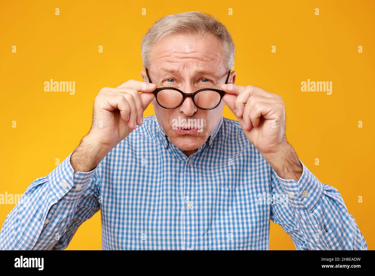 Mature man squinting wearing eyeglasses, looking at camera Stock Photo
