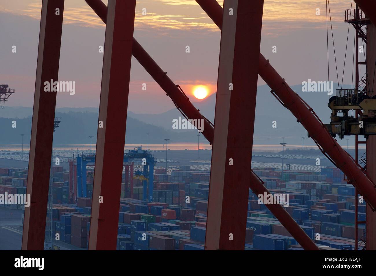 Sunset observed through construction of gantry cranes operated by stevedores. Stock Photo