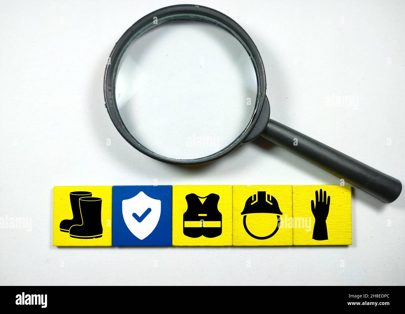 Magnifying glass over the yellow wooden squares with work safety icons ...
