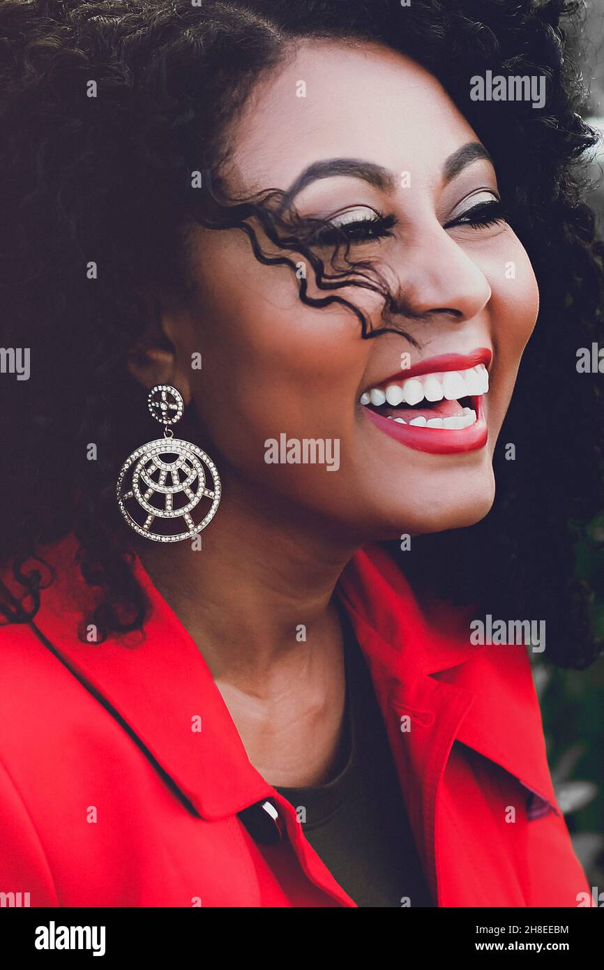 Vertical portrait of a beautiful smiling African female with curly hair and stylish earring Stock Photo